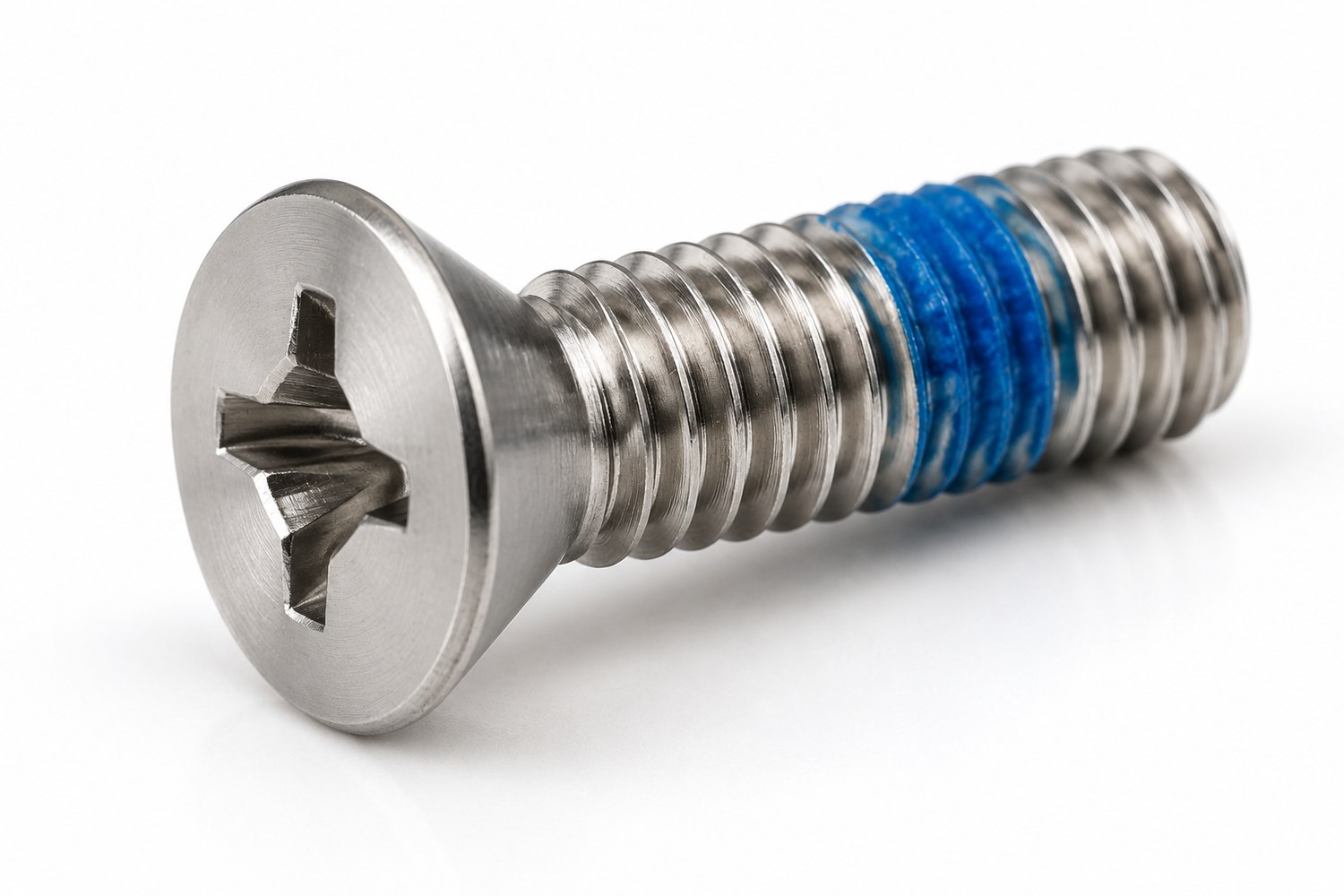 Stainless steel countersunk head Phillips machine screw with a blue pre-applied thread-locking patch on the thread